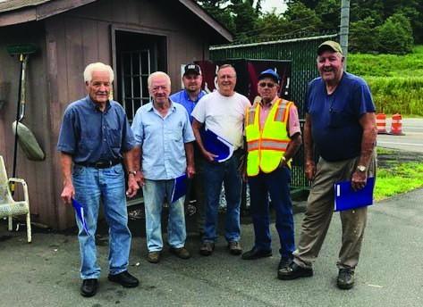 Six men standing in front of a shed